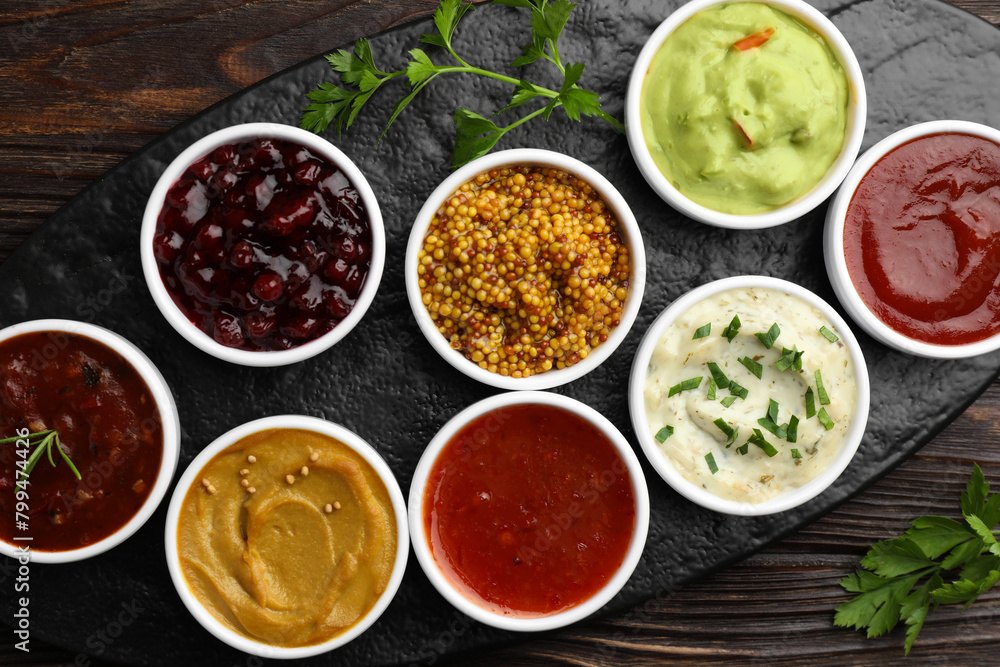 Different tasty sauces in bowls and parsley on wooden table, top view Different tasty sauces in bowls and parsley on wooden table, top view
