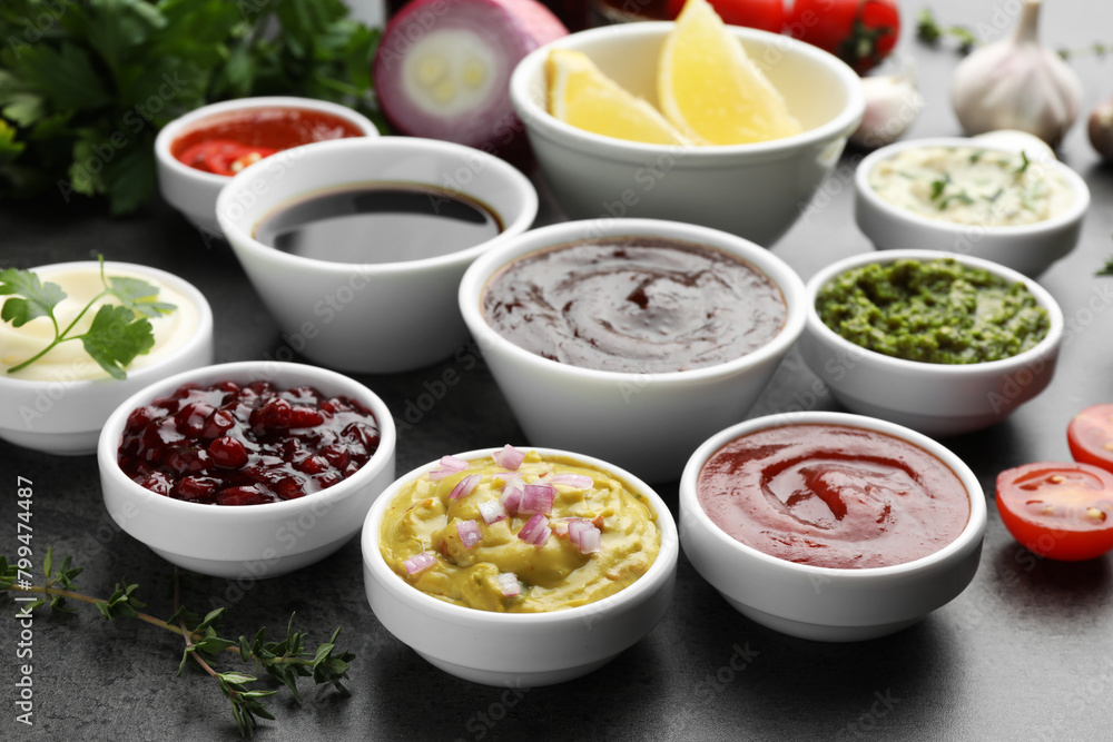 Different tasty sauces in bowls and ingredients on grey table Different tasty sauces in bowls and ingredients on grey table