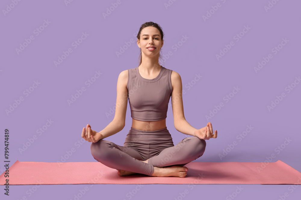 Beautiful young happy sporty woman with yoga mat meditating on purple background Beautiful young happy sporty woman with yoga mat meditating on purple background