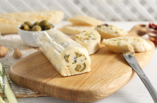 Tasty butter with olives, green onion, bread and knife on white wooden table