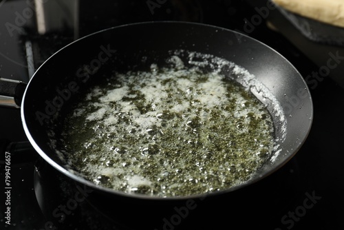 Melting butter in frying pan on black table, closeup