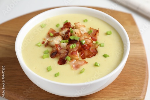 Tasty potato soup with bacon, green onion and croutons in bowl on white table, closeup