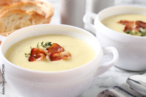 Tasty potato soup with bacon and rosemary in bowls on white table, closeup