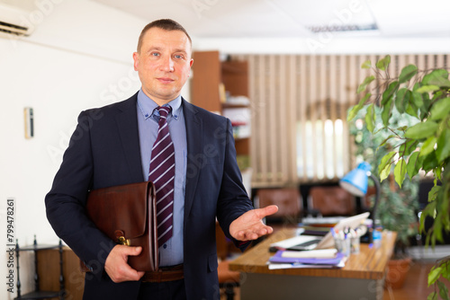Portrait of smiling executive business man inviting visitors to office