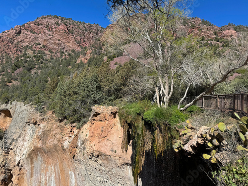 Springtime view of the red rocky mountain landscape in Tonto Natural Bridge State Park in Pine, Arizona with bright blue sky copy space in an area showing the foot bridge, cactus and the small waterfa photo