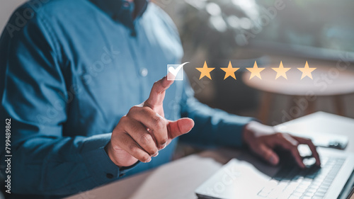 evaluation, feedback, five, management, marketing, opinion, performance, report, reputation, result. A man is giving a thumbs up to a laptop screen with a rating of 5 stars. Concept of satisfaction. © Day Of Victory Stu.