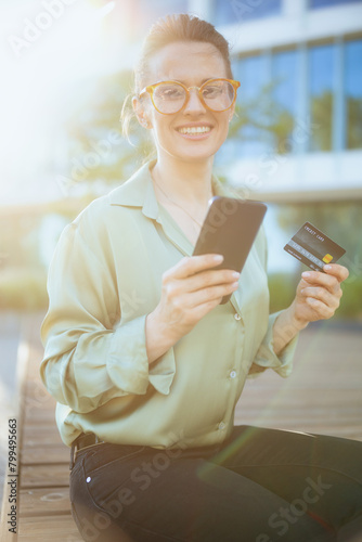 happy business woman in green blouse and eyeglasses using phone