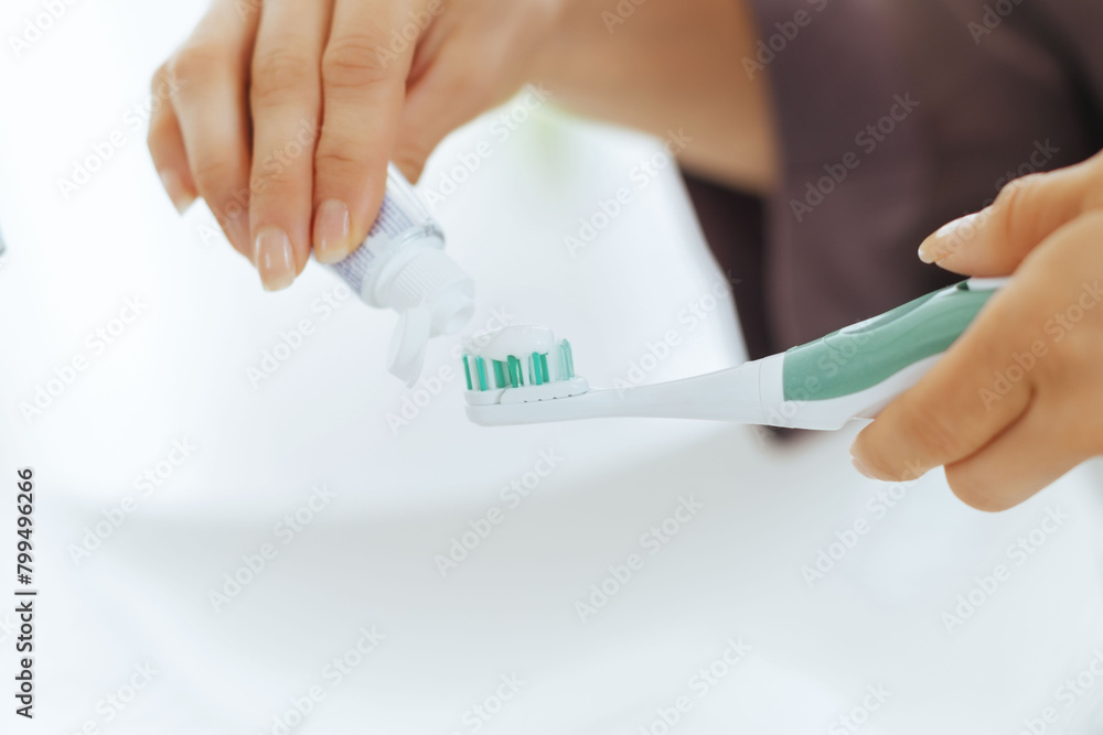 Closeup on young woman squeezing toothpaste on toothbrush