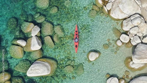The aerial view captures a person kayaking on Lake Tahoe in California, USA. The individual paddles through the water, maneuvering the kayak along the lakes surface. 4K footage.