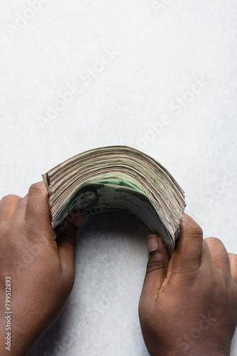 Overhead view of a stack of cash on a table, hand holding a wad of cash