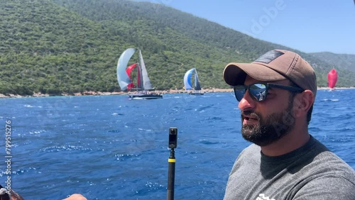 Views from BAYK Bodrum sailing race. Coloful sails,  competition, beautiful weather and friendship. Skipper of boat looking ahead wihile cruising. photo