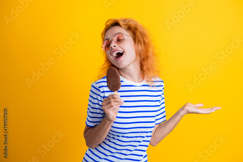 Woman with a cornet ice cream. Delicious waffle cone in summer. Girl eating ice cream in summer. Happy young woman with delicious ice cream in cone isolated on yellow. Presenting product photo
