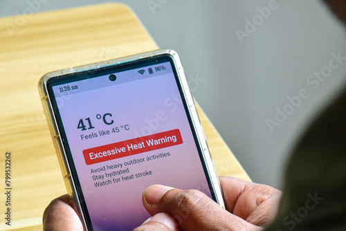 Man using his mobile phone displaying alertness for excessive heat warning. Severe weather El Nino condition. photo