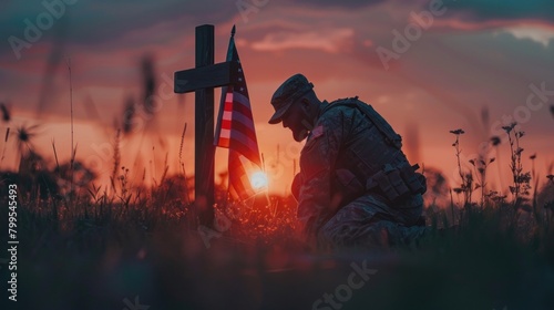 a silhouette of a soldier kneeling beside a battlefield cross, with the American flag draped over it, serving as a poignant tribute to fallen heroes. photo