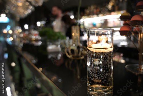 candela accesa in un bicchiere, sul bancone di un bar in una discoteca photo