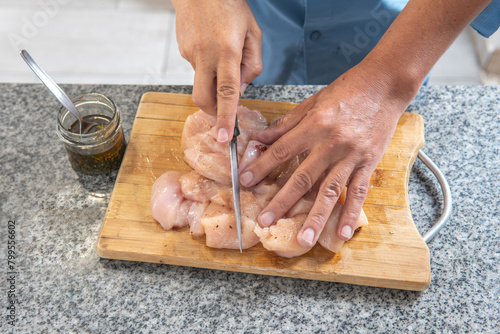 aerial view of man's hands cutting raw chicken