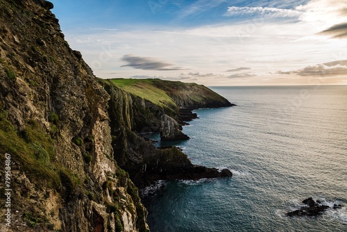 Scenic view of cliffs in Irish coast with green hills at sunset.