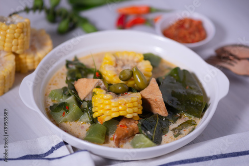 Sayur Lodeh is a vegetable dish made with coconut milk that is typical of Indonesia  especially in Central Java and DI Yogyakarta. Served in a bowl on a white table. Selective focus.