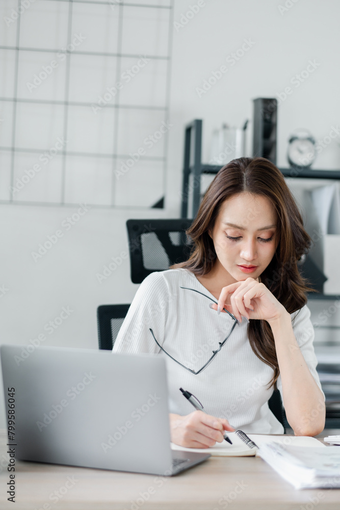 Attentive young businesswoman focuses on her work, reviewing documents with a laptop on a desk in a modern office setting. Attentive young businesswoman focuses on her work, reviewing documents with a laptop on a desk in a modern office setting.