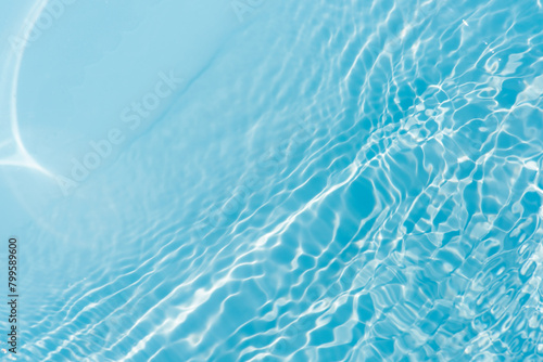 Bluewater waves on the surface ripples blurred. Defocus blurred transparent blue colored clear calm water surface texture with splash and bubbles. Water waves with shining pattern texture background. 