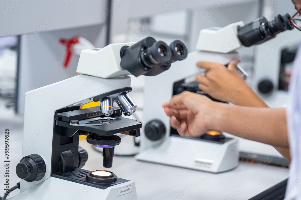A person is using a microscope with a red and white background A person is using a microscope with a red and white background