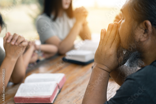 Woman joined hands with her faith group, coming together to pray as a team, unified in their devotion to God and their shared religion. Group christian pray concept.