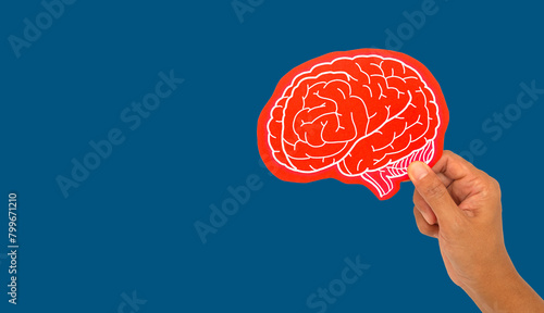 Foto Close-up of a hand holding a brain symbol made from red paper against a blue background