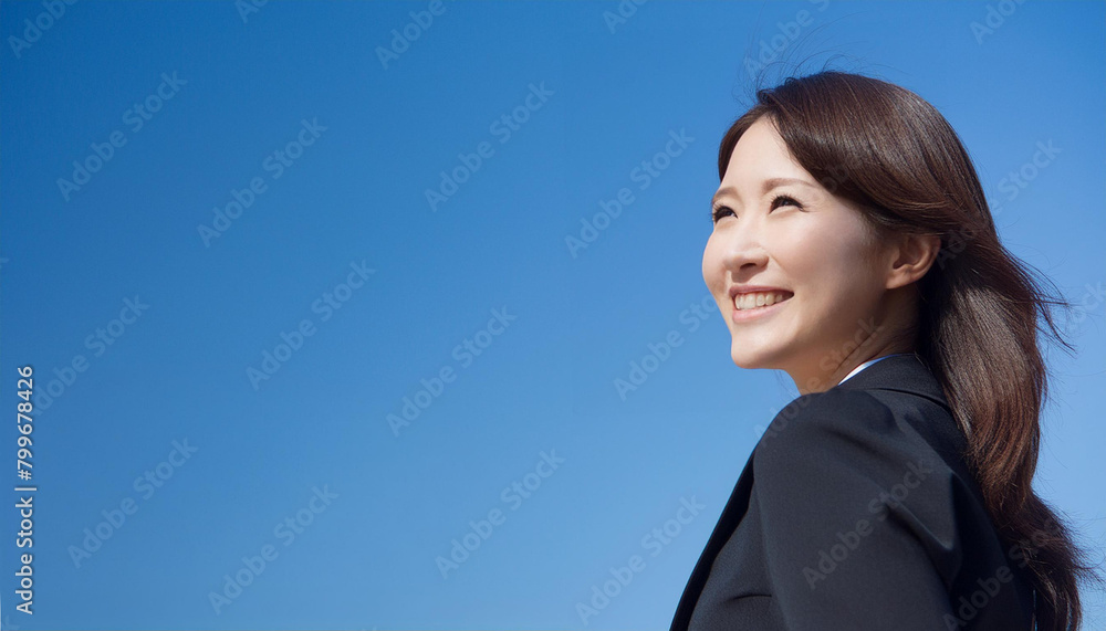 A smiling Asian businesswoman looking up at the blue sky. A smiling Asian businesswoman looking up at the blue sky.