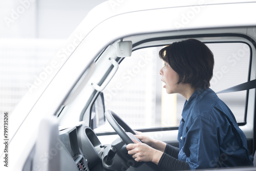 Middle-aged, gruff woman in work clothes driving a truck Surprising image of a traffic accident in the transportation or delivery industry.