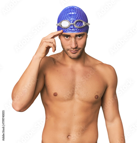 Young Hispanic man with swim gear pointing temple with finger, thinking, focused on a task.