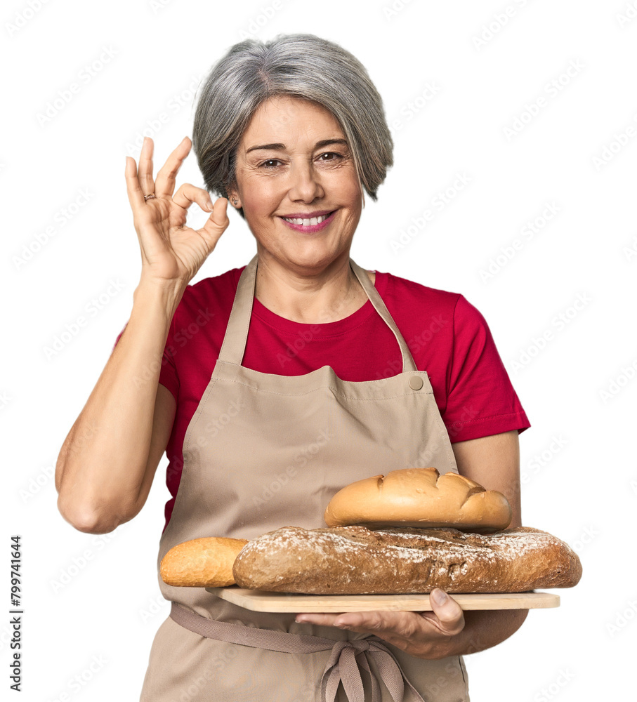 Caucasian mid-age baker with bread loaves cheerful and confident showing ok gesture. Caucasian mid-age baker with bread loaves cheerful and confident showing ok gesture.