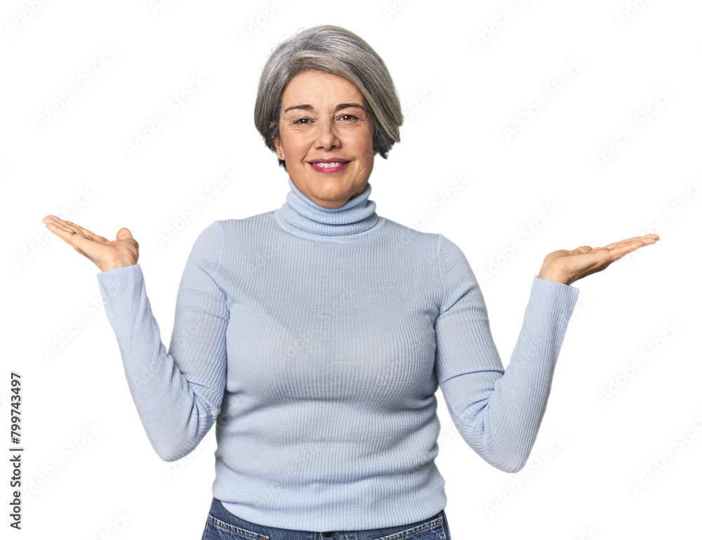 Caucasian mid-age female on studio background makes scale with arms, feels happy and confident. Caucasian mid-age female on studio background makes scale with arms, feels happy and confident.