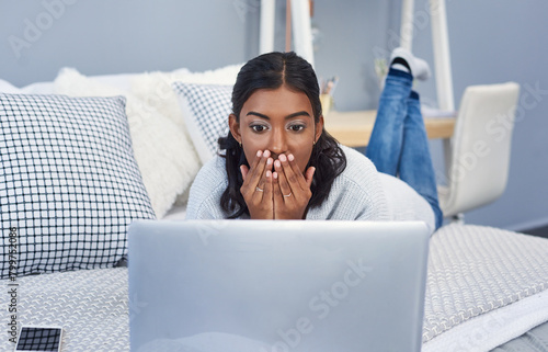 Shock, laptop and woman on bed with scam, phishing or fraud online transaction at apartment. Surprise, upset and female person with cybercrime or identity theft crisis on computer in bedroom at home. photo