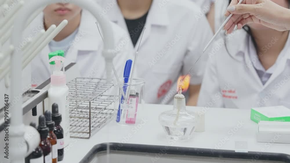 A group of people are in a lab setting, with one person holding a lighter. Scene is serious and focused A group of people are in a lab setting, with one person holding a lighter. Scene is serious and focused