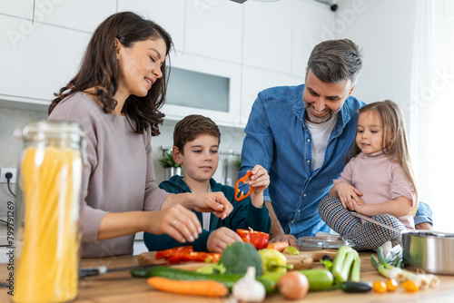 Family with adorable son and daughters gathered in modern kitchen cooking together. Enjoy communication and cookery hobby concept.