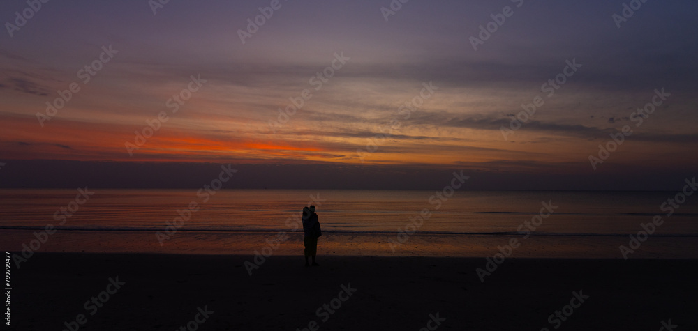 Fototapeta premium Silhouette Dark mother holding baby on the beach with Sunset Nature Coast Landscape Summer 