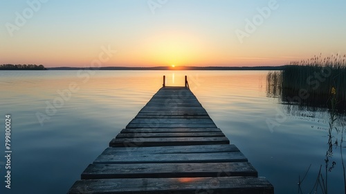 Tranquility at twilight: An old wooden dock stands silently against the backdrop of a stunning sunset over the lake.  photo