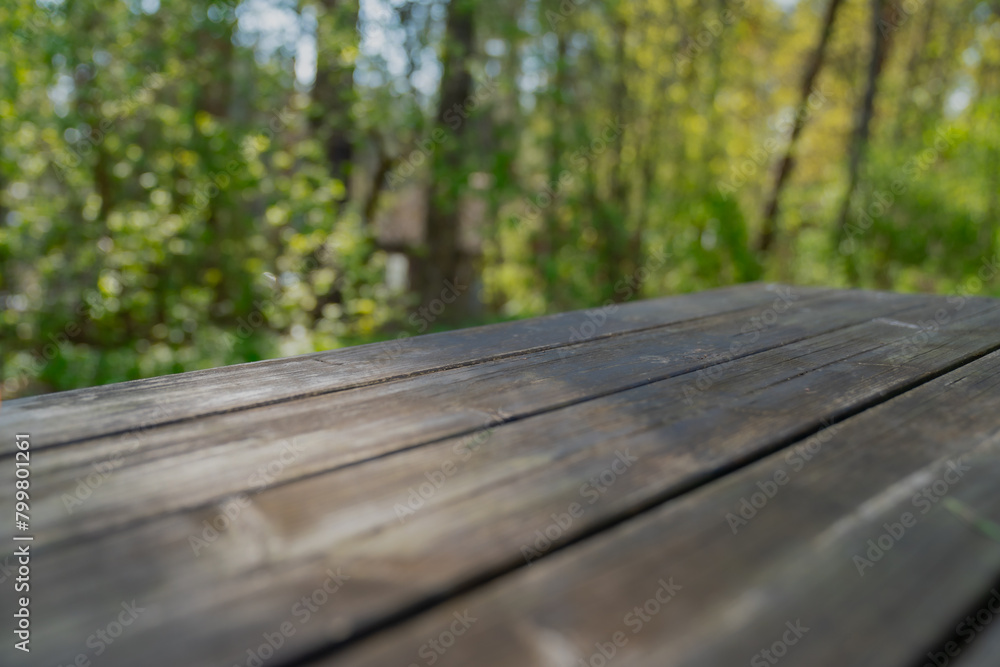 Empty wooden table for product placement with green lush forest background Empty wooden table for product placement with green lush forest background