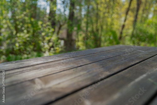Empty wooden table for product placement with green lush forest background
