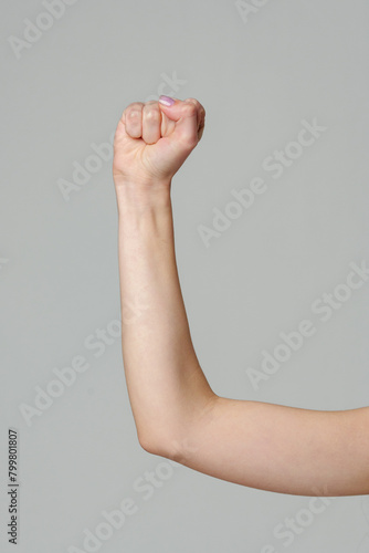 Female hand with clenched fist on gray background