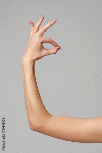 Female hand showing OK sign on gray background