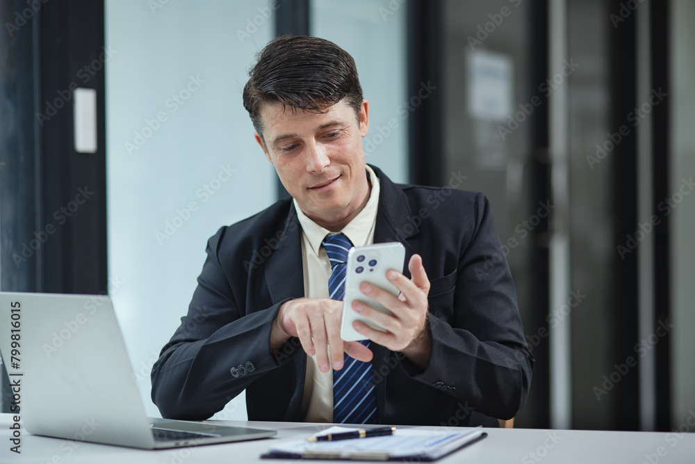 Businessman with smartphone and laptop and analyzing a chart while working in the office, Business and financial concept. Businessman with smartphone and laptop and analyzing a chart while working in the office, Business and financial concept.