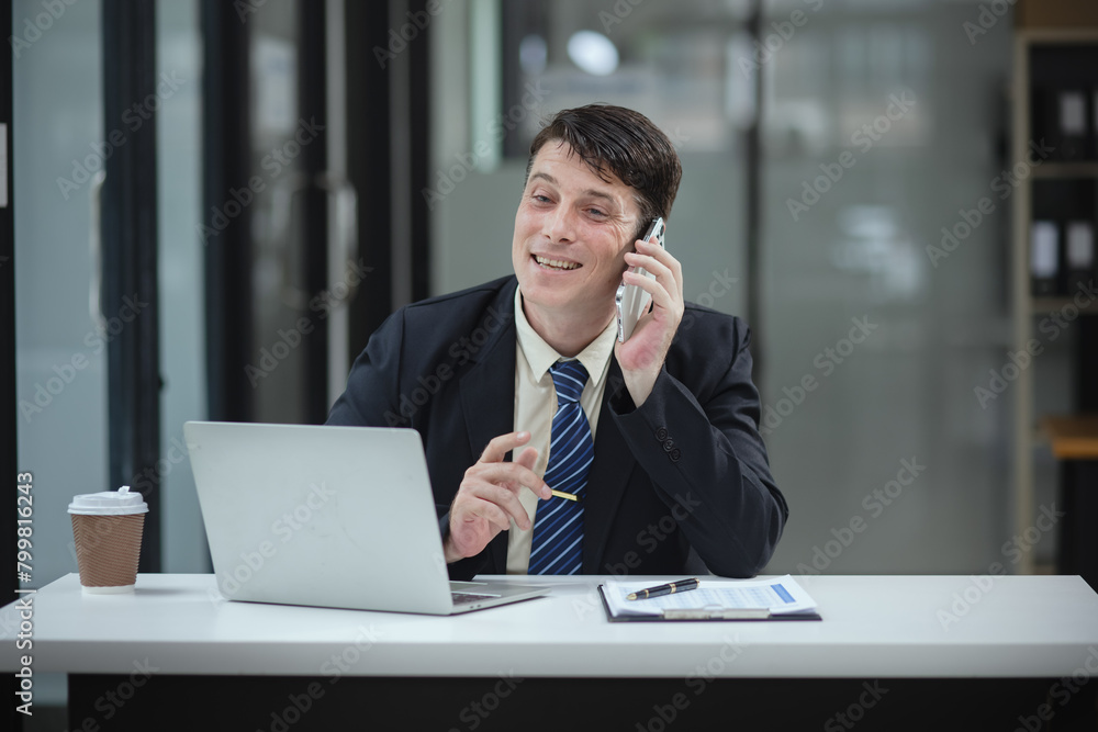 Businessman with smartphone and laptop and analyzing a chart while working in the office, Business and financial concept. Businessman with smartphone and laptop and analyzing a chart while working in the office, Business and financial concept.