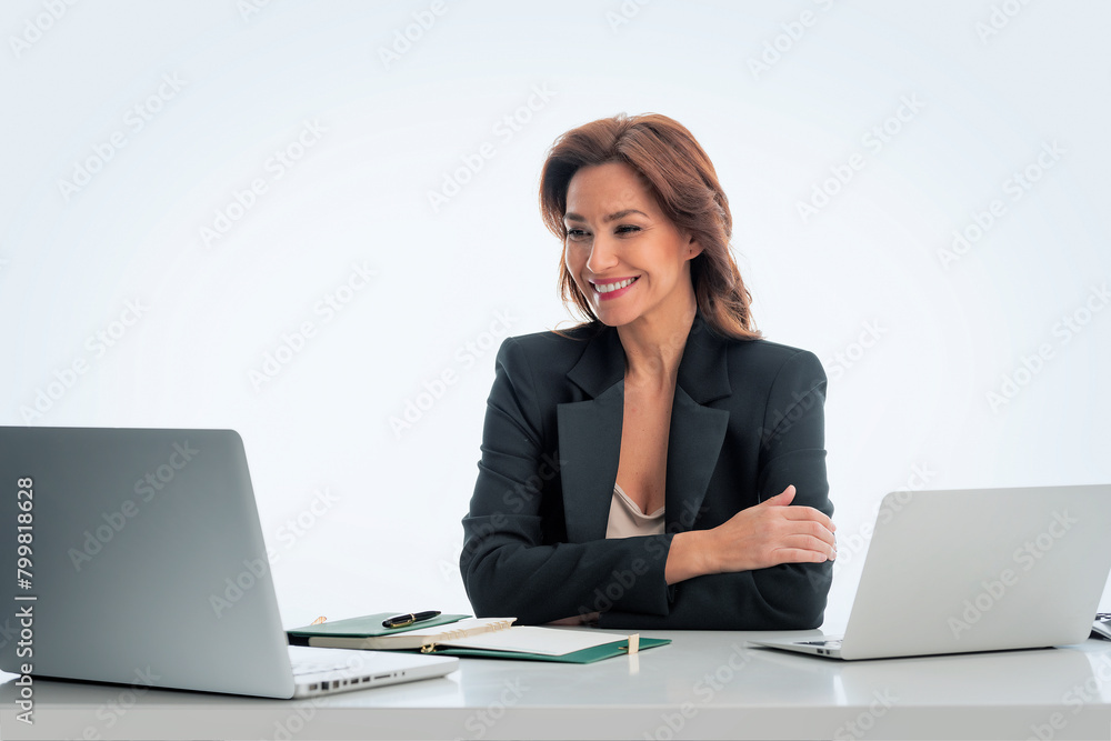 Mid aged businesswoman sitting at desk and using laptops Mid aged businesswoman sitting at desk and using laptops