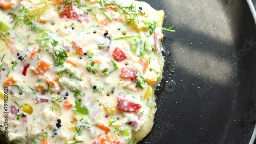 pancake or indian chilla or uttapam prepared on black pan in kitchen with sunlight photo