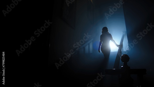 Beauty and form. The silhouette of a beautiful, young woman against a dark background is climbing up the old stairs.