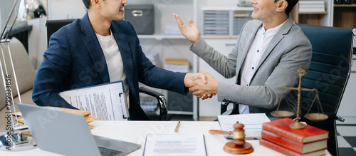 Asian Man lawyer hand and Humen client shaking hand collaborate on working agreements with contract documents at office. photo