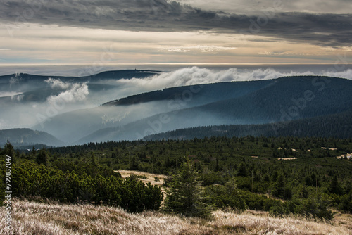 Krkonoše mountain hills with dramatic cloud cover and fog on an early autumn day
