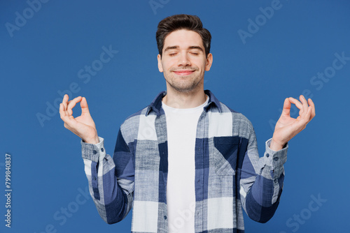 Young Caucasian man wear shirt white t-shirt casual clothes hold spreading hands in yoga om aum gesture relax meditate try to calm down isolated on plain blue cyan background studio Lifestyle concept