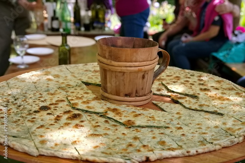 Soparnik - traditional Croatian food on big wooden plate with wooden mug in the middle